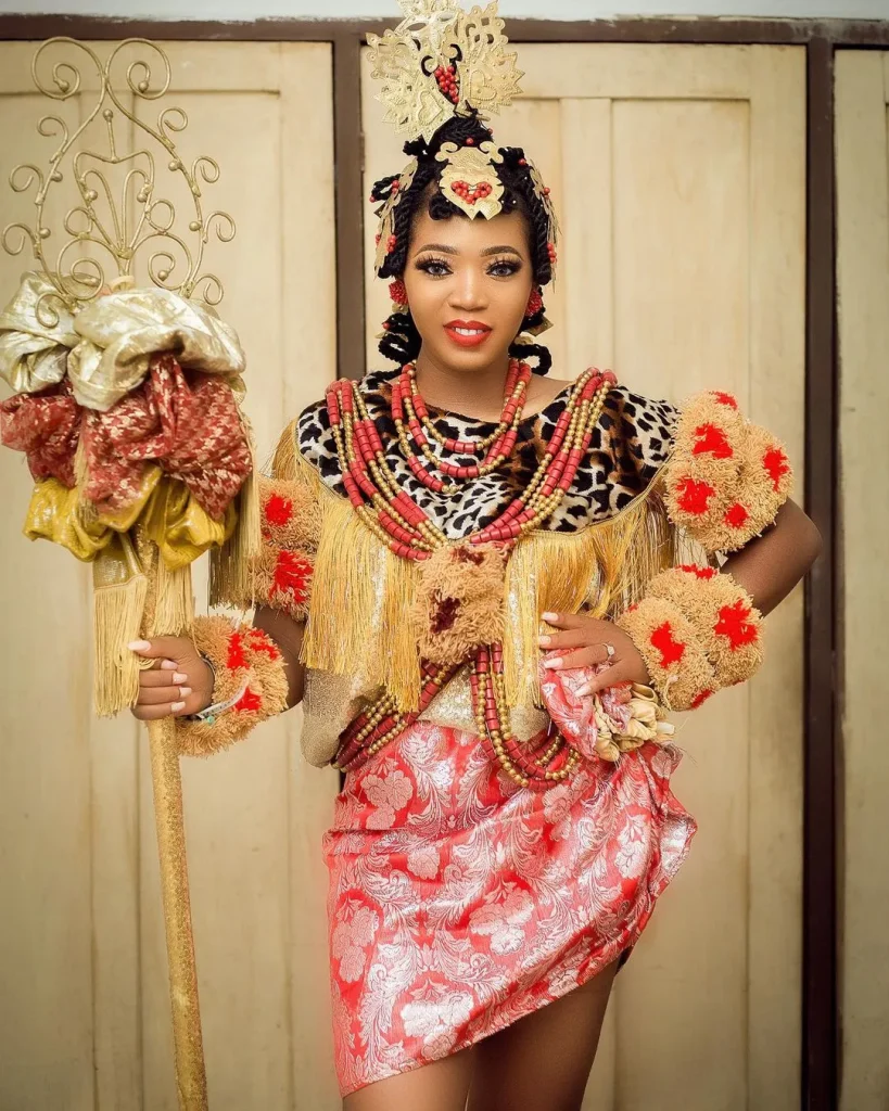 Efik Bride In Gold and tiger print Onyonyo Dress, Decorated Hair, Coral Beads and Staff