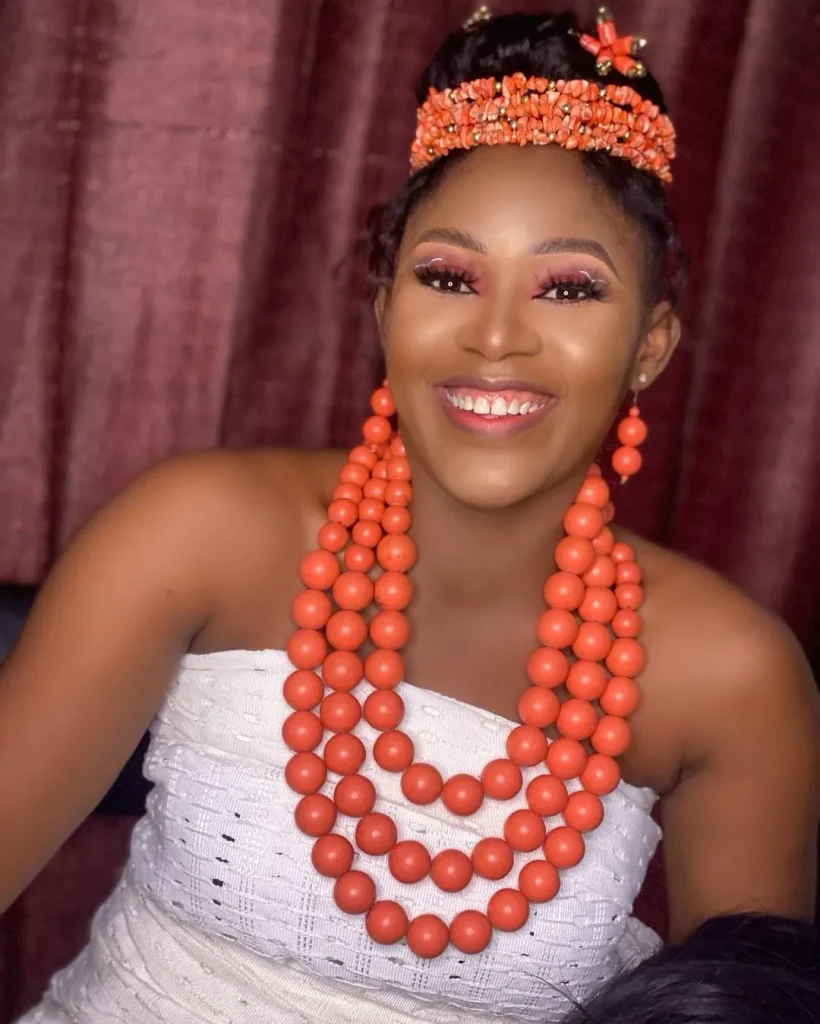 Bride in lovely white igbankwu outfit, adorned with coral beads and holding a horse tail.